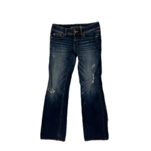 Mörkblå bootcut jeans - Snygga trendiga mörkblå bootcut jeans med slitna detaljer och låg midja. Passar främst storlek s