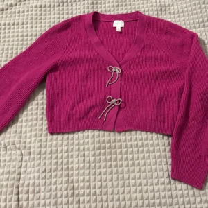 Rosa ribbad kofta med knyt - Säljer en söt rosa ribbad kofta med knyt framtill. Koftan är croppad och har långa ärmar, perfekt för lager på lager-stilen. Ett måste för garderoben! Om ni vill se den på, skriv gärna!