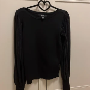 Fest tröja med ballong armar  - Snygg svart tröja från Vero moda med unika plisserade ärmar som ger en elegant touch. Tröjan har en rund halsringning och långa ärmar med ribbade muddar. Perfekt för en stilren look eller en mer festlig. 55cm lång från axlarna och ner. Använd 1 gång. 