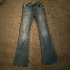 Blå bootcut jeans - Säljer ett par klassiska blå bootcut jeans med låg midja. De har en snygg tvättad look. Jeansen har fickor både fram och bak samt en knapp- och dragkedjestängning. Och som du ser är dom lite slitna❤️