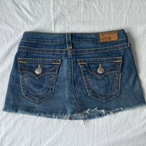 Jeanskjol från True Religion - Snygg jeanskjol från True Religion med stenar på framfickorna och sömdetaljer. Köpt second hand och är i bra skick endast använd 2 gånger.
