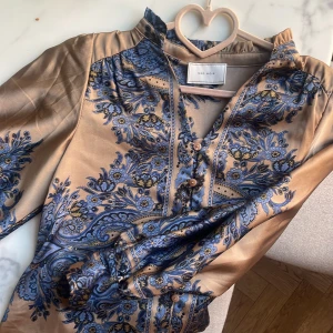 Blus från Jackie, märke Neonoir - Blus i guldbeige med blått mönster.Använd en gång
