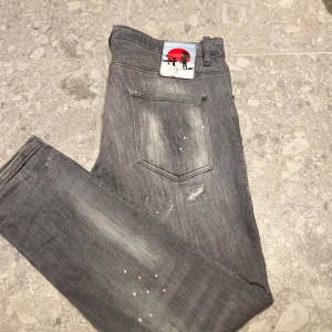 Grå jeans från Dsquared2 - Snygga grå jeans från Dsquared2 med slitna detaljer och en cool patch på baksidan. Perfekta för en avslappnad stil med en edgy touch. Nypris ligger på cirka 6000-7000kr
