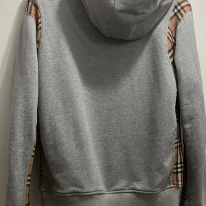 Grå Burberry tjocktröja.  - Säljer en grå Burberry tröja. Tröjan har en justerbar huva och praktiska fickor framtill. Använd fåtal gånger. Pris kan diskuteras vid snabb affär. 