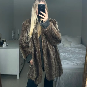Brun äkta pälsjacka - Säljer en snygg brun äkta pälsjacka med lång ärm, köpt vintage. Perfekt för att hålla sig varm och stilren under kyliga dagar. Jackan har en klassisk design som passar till många olika outfits.