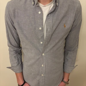 Grå Ralph Lauren skjorta - Snygg grå skjorta från Ralph Lauren i slim fit i väldigt fint skick🤩. Perfekt för en stilren look. Nypris ca: 1499kr💰 Storlek: S/M (fast det står M i skjortan)