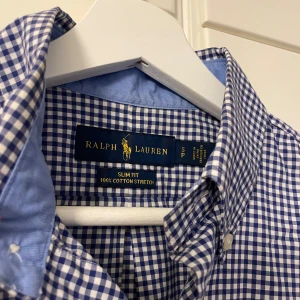 Rutig skjorta från Ralph Lauren - Snygg blå och vit rutig skjorta från Ralph Lauren i slim fit. Tillverkad av 100% bomull med stretch för extra komfort. Storlek: S. Hör av er vid eventuella frågor / funderingar! 🙏