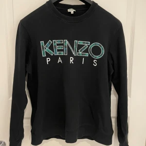 Kenzo - Snygg svart Kenzo tröja med det ikoniska logotyptrycket i turkos och vitt på framsidan.