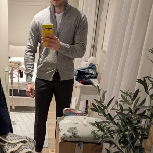 Grå kofta från Massimo Dutti stl M - Säljer en stilren grå kofta med dubbel dragkedja, som kan öppnas uppe och nere. Perfekt för lager-på-lager och passar till många olika outfits. Från Massimo Dutti i stl Medium.