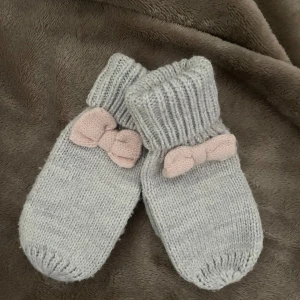 Grå stickade vantar med rosett från H&M - Barn vantar från H&M med en rosa rosett på ovansidan. Vantarna har används fåtal gånger. 