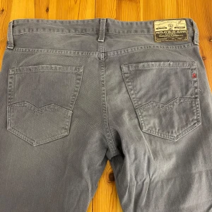 Grå jeans från Replay - Snygga grå jeans från Replay med klassisk femficksdesign och en diskret logga på bakfickan. Byxorna har en rak passform och är tillverkade i ett slitstarkt material. Storlek W34L34. 
