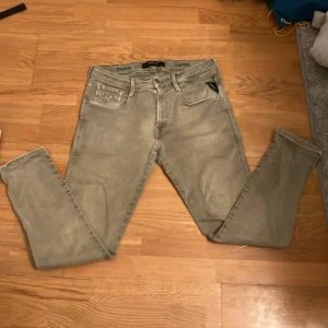 Beige gråa Replay Hyperflex Anbass Jeans - Snygga beige gråa jeans från Replay i modellen Anbass. Dessa jeans har en tight passform och är tillverkade i det bekväma Hyperflex-materialet. Perfekta för en stilren look. Storlek W29 L30