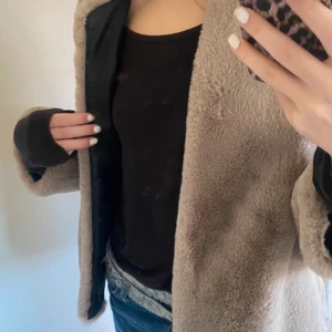 Beige teddyjacka från Zara Woman - Mysig beige teddyjacka från Zara Woman med svart innerfoder. Perfekt för kyliga dagar med sin fluffiga textur och stilrena design. Jackan har en klassisk passform och är lätt att matcha med olika outfits.