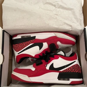 Nike Air Jordans Legacy 312 - Snygga Nike Air Jordans i en klassisk röd och vit färgkombination med svarta detaljer. Skorna har en ikonisk design vid snörning och den välkända Jumpman-loggan på hälen. Perfekta för sneakerheads som vill ha en stilren look. Nypris ca 2000kr