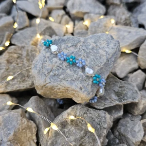 ~Handgjort blått armband~ - Ett armband med små blå blommor och sötvattenspärlor. Armbandet har en design som passar bra till både vardag och speciella tillfällen. Armbandet har smyckeslås och kedja i silver.