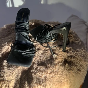 Svarta höga stiletto klackskor med snörning - Eleganta svarta klackskor med smal snörning och fyrkantig framdel. Perfekta för en classy eller het look. Har aldrig använts!