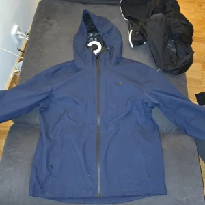 Blå vindjacka från Whistler - Säljer en blå vindjacka från Whistler med huva och dragkedja. Jackan är perfekt för blåsiga dagar och har en funktionell design med hög komfort. Passar bra för utomhusaktiviteter. Den är testad 1 gång men den va för stor därav att jag säljer den (byte går). Nypris 2499 | 