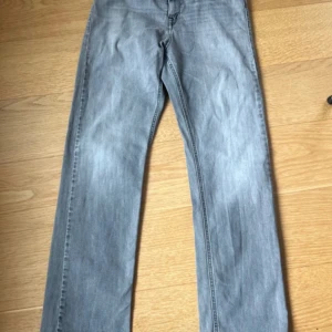 Grå jeans från Replay Tchad 16 A  - Snygga grå jeans från Replay med en klassisk femficksdesign. De har en dragkedja och knapp framtill samt Replay-logga på insidan av linningen. Perfekta för en stilren look. Modell: Tchad 16 A. Är i jättebra skick. 