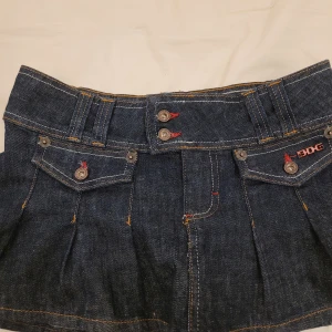 Kort jeanskjol  - Snygg jeanskjol från urban outfiters i mörkblå med dekorativa fickor och knappar framtill. Kjolen har en kort och trendig design som passar perfekt för en avslappnad stil. Köptes för ca 600 och är endast använd 3 gånger. Står storlek XS men passar mig som bär S💕