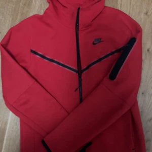Röd Nike tech fleece kofta - Säljer en snygg Röd Nike tech fleece i storlek S. Använd två gånger och passar bra i storlek.