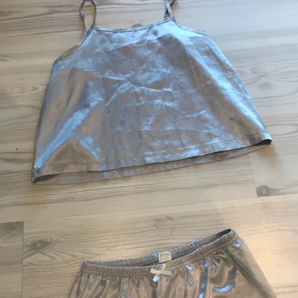 Säljer en fin silvrig pyjamas. Inte använd så mycket. Båda delar i storlek 150. Spetsdetaljer längs ner på byxorna och även en liten rosett vid midjan på byxorna. . Muu.