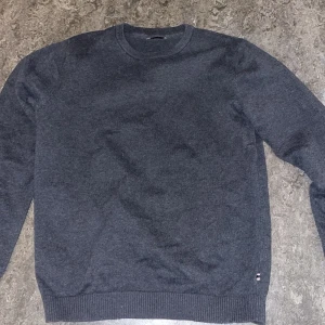 Mörkgrå tröja från Jack & Jones - Säljer en stilren mörkgrå tröja från Jack & Jones. Tröjan har en klassisk rund hals och långa ärmar. Perfekt för en avslappnad look.