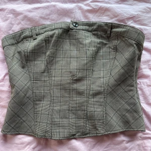 Rutig korsett i beige  toner - Snygg rutig korsett i grå toner med knäppning fram. Perfekt för att ge en stilren look. Passar bra till både jeans och kjol. (Alldeles för stor på bröstet för mig, därmed säljs) 