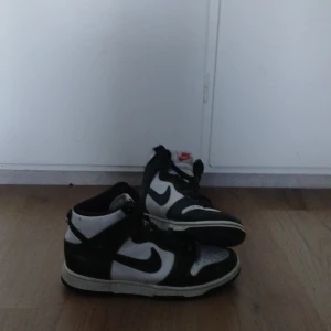 Nike Dunk panda - Säljer ett par klassiska Nike Dunk pandas. Skorna har en stilren design med snörning och är perfekta för en sportig look. De har några tecken på användning(bild 2 & 3) men är fortfarande snygga och bekväma.