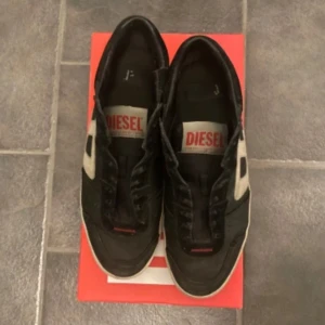 Diesel skor - Säljer ett par tvärfeta svarta Diesel s-leroji low i bra skick. Nypriset är runt 2300 mitt pris är 899. Skorna har snörning och är perfekta för vardagsbruk. De är bekväma och stilrena, passar till det mesta! Skolåda ingår. Priset är inte skrivet i sten! Byten är intressant🤔
