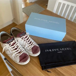 Phillip model skor  - Snygga vita sneakers från Philippe Model med vinröda detaljer och snörning. Skorna har en unik design med märkets logga på sulan. Perfekta för en stilren look. Nypris 2699kr mitt pris 1099kr hör av er vid frågor osv ‼️