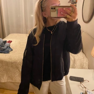 Blå marinblå bomberjacka - Snygg svart bomberjacka med dragkedja framtill och fickor på ärmarna. Perfekt för en cool och avslappnad stil.