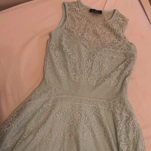 Mintgrön spetsklänning från Club L - Säljer en elegant mintgrön klänning från Club L med vacker spetsdesign. Klänningen är ärmlös och har en rund halsringning. Perfekt för en somrig look med sin fina spets och mjuka färg.