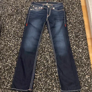 True Religion Jeans Super T - Super T, straight fit. Står 31 på taggen men passar mer som 32. Lite distressed vid flapsen men bra skick overall. (Innerben 83cm) (Ytterben 114) (Midja tvärsöver 41cm) (Benöppning 20,5cm)