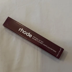 Peptide Lip Tint i färgen Espresso från Rhode - Säljer en Peptide Lip Tint från Rhode i färgen Espresso. Denna läpprodukt ger en skir nyans och återfuktar läpparna med peptider. Perfekt för en naturlig look med en hint av färg.