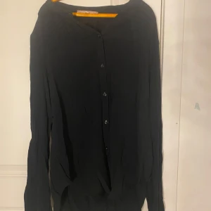 Svart kofta med knappar - Säljer en stilren svart kofta med knappar framtill. Perfekt för lager-på-lager och passar till många olika outfits. Koftan har långa ärmar och en klassisk design.