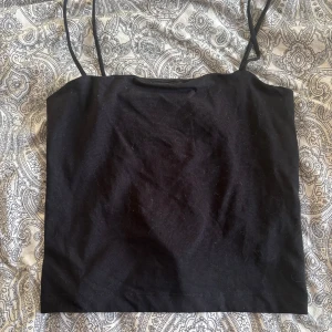 Svart linne från Gina Tricot - Säljer en stilren svart linnetopp från Gina Tricot. Toppen har smala axelband och är perfekt för varma dagar. Enkel och mångsidig design som passar till det mesta. Aldrig använd, hör av dig vid intresse❤️