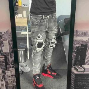 Grå ripped jeans - Snygga grå jeans med slitningar och hål för en trendig look. De har en skinny passform och är perfekta för en avslappnad stil. Jeansen har klassisk femficksdesign och är tillverkade i denim.