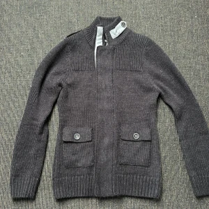 Stickad Cardigan - Säljer nu en sjukt fet stickad Cardigan. I storlek M. Riktigt stilig med knappar och är ny! Perfekt nu för kallare dagar och vår. Den är svart och grå! 