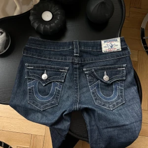 True Religion jeans - Så snygga true religion jeans i den lågmidjade modellen. Jeansen är i fint skick förutom att dragkedjan gått av (bild 4), den går fortfarande att att använda precis som vanligt om man stoppar i den (bild 5). Lite slitna nertill.  Nypris ca 1600kr. 