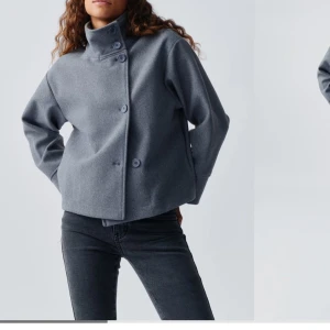 Grå ulljacka med knappar - Säljer en stilren grå ulljacka med knappar framtill. Jackan har en hög krage och långa ärmar, perfekt för kyliga höst- och vårdagar. Den har en modern och minimalistisk design som passar till det mesta. Superfin och i bra skick!
