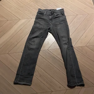 Grå jeans från Replay - Säljer ett par grå jeans från Replay. De har en snygg, sliten look med små revor på framsidan. Perfekta för en casual stil. Jeansen har en klassisk femficksdesign och är gjorda i ett bekvämt material. Kan gå ner i pris 