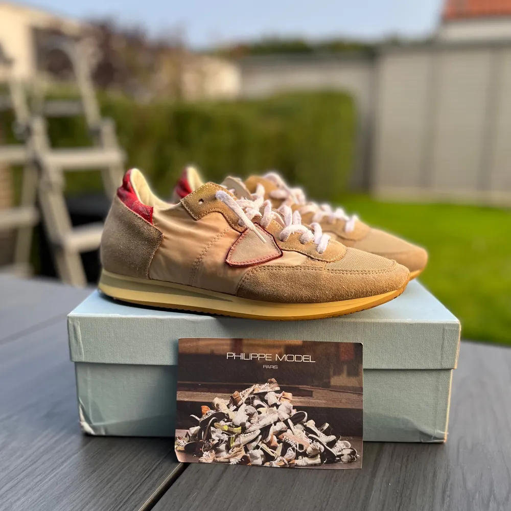 Säljer ett par snygga beige sneakers från Philippe Model. De har en stilren design med mockadetaljer och en röd accent på hälen. Skorna har vita snören och en bekväm gummisula. Perfekta för både vardag och fest Pris kan även diskuteras vid snabbt köp. Skor.