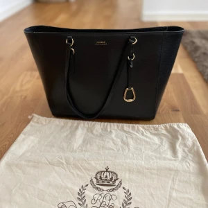 Lauren Ralph Lauren Väska - min älskade väska från Lauren Ralph Lauren behöver en ny ägare, har inte användning för den längre. den är fint skick men finns lite små skavanker som ej stör utseendet kolla gärna bilderna