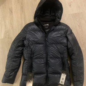 UBR Lighweight Down Jacket Navy storlek S - Helt ny lighweight down jacket från märket UBR. Storlek S. Fylld med gåsdun och väger endast 230 gram, nypris ca 5000kr. 