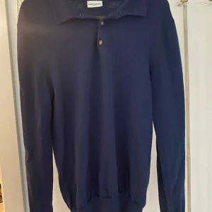 Mörkblå pikétröja från John Henric  - Snygg mörkblå pikétröja från John Henric  med klassisk krage och knappar. Perfekt för en stilren look. Tröjan har långa ärmar och är tillverkad i ett mjukt material.