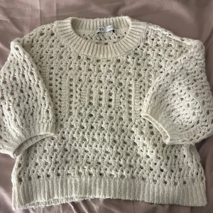 beige stickad tröja från Zara - Säljer en beige stickad tröja från Zara med ett snyggt hålmönster. Tröjan har trekvartsärmar och ribbade kanter. Väldigt fin men använd