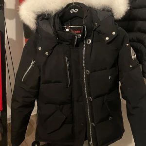 Svart dunjacka från Moose Knuckles - Säljer nu min Mose Knuckles jacka, då ja inte har användning av den. Använt den under en vinter, jackan är i ganska bra skick. Dock har den ett litet hål som går att sy, men inget märkvärt. Kontakta för frågor, endast seriösa köpare!