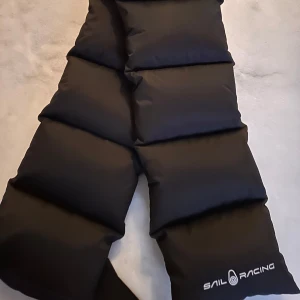 Svart pufferhalsduk från Sail Racing - Snygg svart pufferhalsduk från Sail Racing. Halsduken har en quiltad design och är perfekt för kyligare väder. Den har en stilren look med logotypdetalj.