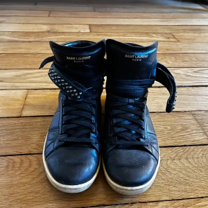 Saint Laurent Sl/100h - Höga studded lädersneakers från Saint Laurent. Ingen låda. Väldigt bra skick, lite smuts men inga skador.