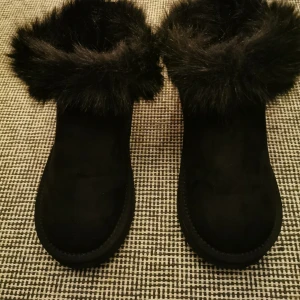 Svarta boots med pälsdetalj (uggsliknande)  - Snygga svarta boots (uggsliknande) från Linear (Din Sko) med mjuk pälsdetalj runt skaftet. Perfekta för kyliga dagar och ger en stilren look. De är tillverkade i syntetmaterial och har en bekväm passform. Helt Nya. Stl 39 finns i Hökarängen/Farsta 
